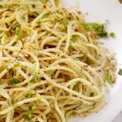Un piatto di spaghetti alla carrettiera, conditi con aglio, olio, peperoncino e prezzemolo fresco, accompagnati da pane rustico.