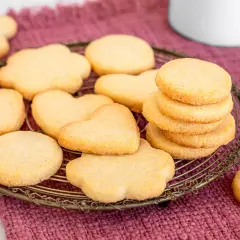 Biscotti classici a forma di cuore e fiore, impilati su una gratella dorata, pronti per essere gustati.