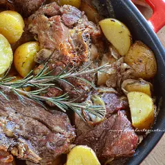 Succulento agnello al forno con patate dorate e rosmarino, un piatto che profuma di casa e tradizione.