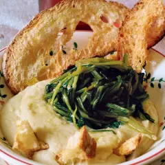 Piatto di fave e cicoria con crostini di pane abbrustolito. Un classico della cucina italiana, gustoso e salutare.