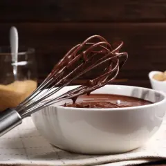 Frusta ricoperta di golosa crema pasticcera al cioccolato, pronta per essere gustata.