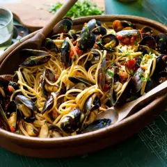 Un invitante piatto di spaghetti con le cozze, condito con pomodoro e prezzemolo, pronto per essere gustato.