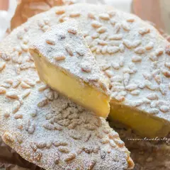 La crostata della nonna, con la sua crema gialla e i pinoli tostati, è un dolce che profuma di casa.
