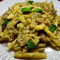 Pasta con carciofi alla siciliana, un piatto saporito e profumato, guarnito con foglie di menta fresca.