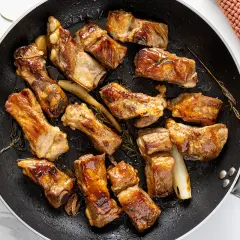 Costine di maiale in padella, dorate e succulente, profumate al rosmarino. Un piatto invitante pronto per essere gustato.
