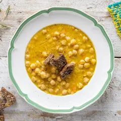 Un piatto invitante di zuppa di ceci, guarnito con crostini di pane scuro e accompagnato da fette di pane integrale.