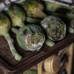 Carciofi freschi su un tagliere di legno, pronti per imparare come congelare i carciofi e conservarli per l'inverno.