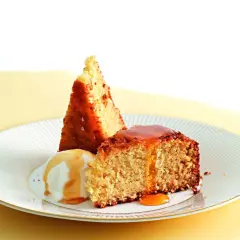 Fetta di torta al cocco con gelato alla vaniglia e sciroppo dorato.