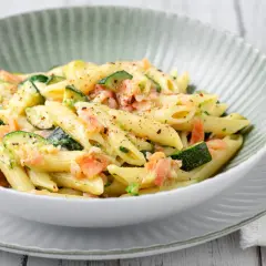 Penne con salmone e zucchine, un piatto cremoso e saporito, condito con erbe fresche e pepe nero.