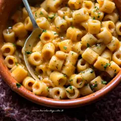 Un piatto fumante di pasta e fagioli, la ricetta della nonna, con ditalini e fagioli in un sugo cremoso, guarnito con prezzemolo tritato.