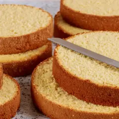 Dischi di pan di spagna pronti per essere farciti. Una lama affilata è appoggiata su uno strato, invitando a creare dolci delizie.