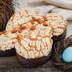 Colomba pasquale con glassa croccante, mandorle e zuccherini, decorata con uova e nidi di Pasqua.