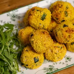 Polpette di zucchine al forno dorate e croccanti, servite su un piatto con rucola fresca.