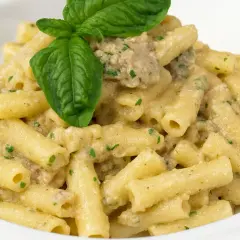 Piatto di pasta con melanzane in bianco, condita con una cremosa salsa e guarnita con basilico fresco.