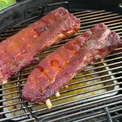 Costine al forno succulente e speziate che cuociono lentamente su una griglia, pronte per essere gustate.