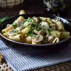 Piatto fumante di pasta funghi e salsiccia, guarnito con prezzemolo fresco. Un classico confortante.