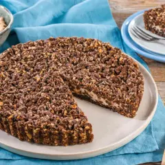 Sbriciolata ricotta e cioccolato con croccante copertura di nocciole. Una fetta invitante attende su un piattino.