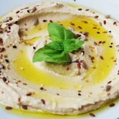 Cremoso hummus di ceci, condito con olio d'oliva, semi misti e una foglia di basilico fresco.