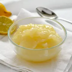 Una ciotola di cremosa crema di limoncello, con limoni freschi affettati accanto.