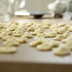Orecchiette fatte in casa, pronte per essere cucinate. Un mare di pasta fresca su un tagliere di legno.
