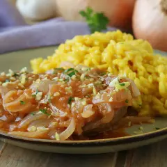 Un succulento ossobuco alla milanese, tenero e saporito, servito con un cremoso risotto giallo.