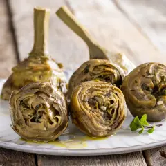 Carciofi alla romana ricetta: carciofi stufati con erbe aromatiche e aglio su un piatto bianco, pronti per essere gustati.