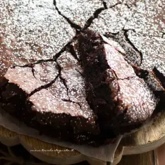 Una deliziosa torta al cioccolato fondente, con una crosta crepata e cosparsa di zucchero a velo, pronta per essere gustata.