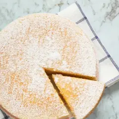 Torta 7 vasetti soffice e spolverata di zucchero a velo, pronta per essere gustata. Un pezzo è già stato tagliato.