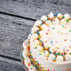 Torta bianca decorata con panna e confettini colorati, un esempio di torte di compleanno particolari per una festa allegra.