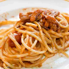 Spaghetti alla chitarra conditi con un ricco sugo di carne e pomodoro, un piatto invitante e saporito.