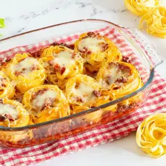 Nidi di tagliatelle al forno con ragù e formaggio fuso, pronti per essere gustati.