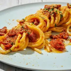 Spaghetti alla ghigliottina conditi con pomodorini secchi e pangrattato, un piatto invitante e saporito.