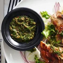 Costolette d'agnello con salsa verde senza uovo, servite su un letto di finocchio e cipolla rossa.