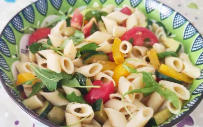 Un piatto colorato di pasta con verdure fresche: zucchine, pomodori, peperoni e rucola.