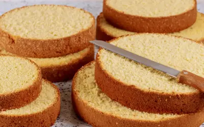 Dischi di pan di spagna pronti per essere farciti. Una lama affilata è appoggiata su uno strato, invitando a creare dolci delizie.