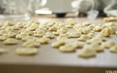 Orecchiette fatte in casa, pronte per essere cucinate. Un mare di pasta fresca su un tagliere di legno.