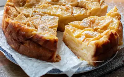 Una deliziosa torta di mele dorata, con fette di mela caramellate in superficie e una spolverata di zucchero a velo.