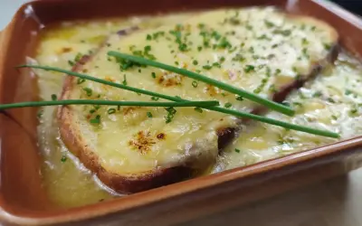 Zuppa di cipolle fumante, con crostini dorati e formaggio filante, guarnita con erba cipollina fresca.