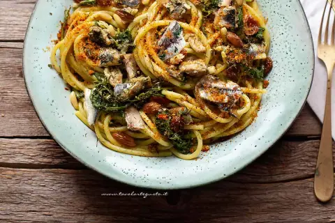 Un piatto invitante di pasta con le sarde, condita con erbe aromatiche, pinoli e pangrattato tostato.