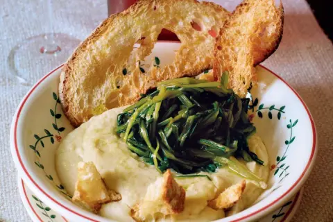 Piatto di fave e cicoria con crostini di pane abbrustolito. Un classico della cucina italiana, gustoso e salutare.