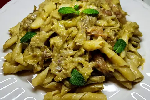 Pasta con carciofi alla siciliana, un piatto saporito e profumato, guarnito con foglie di menta fresca.