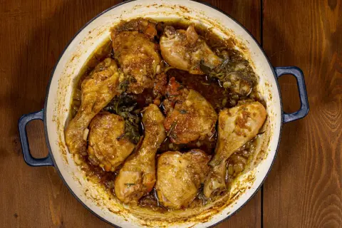 Succulento pollo alla birra cotto in una casseruola, con pezzi dorati e succosi immersi in un sugo aromatico con erbe.
