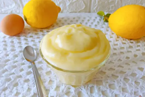 Crema pasticcera al limone, soffice e profumata, pronta per essere gustata. Accanto, un uovo e limoni freschi.