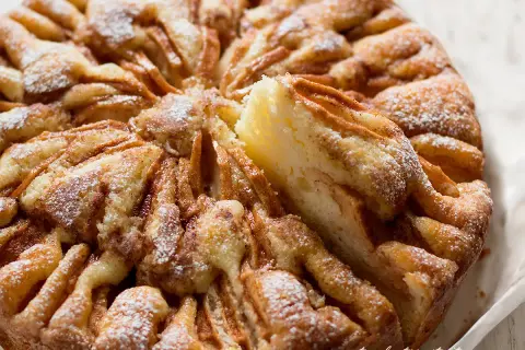 Una torta di mele umida e soffice, con un impasto dorato e mele caramellate, spolverata di zucchero a velo.