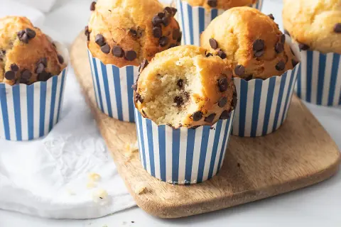 Muffin con gocce di cioccolato, perfetti per la friggitrice ad aria. Uno è stato morso, mostrando l'interno soffice.