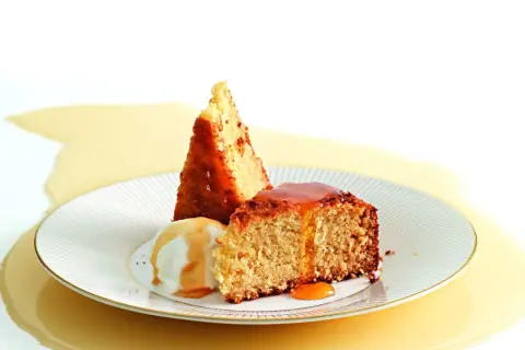 Fetta di torta al cocco con gelato alla vaniglia e sciroppo dorato.