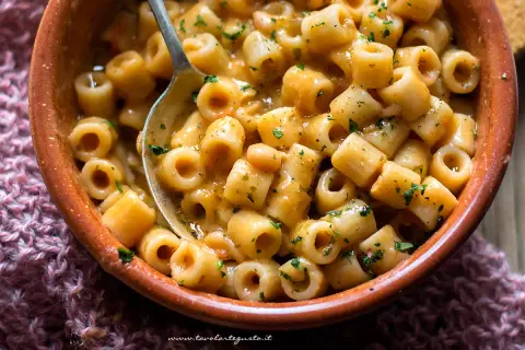 Un piatto fumante di pasta e fagioli, la ricetta della nonna, con ditalini e fagioli in un sugo cremoso, guarnito con prezzemolo tritato.