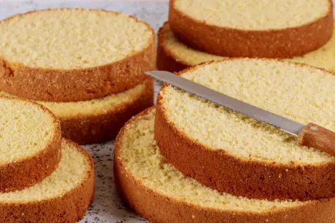 Dischi di pan di spagna pronti per essere farciti. Una lama affilata è appoggiata su uno strato, invitando a creare dolci delizie.