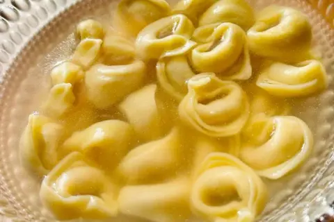 Un primo piatto caldo e confortante: tanti tortellini in brodo dorato, pronti per essere gustati.