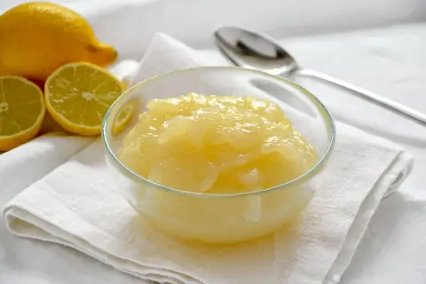 Una ciotola di cremosa crema di limoncello, con limoni freschi affettati accanto.